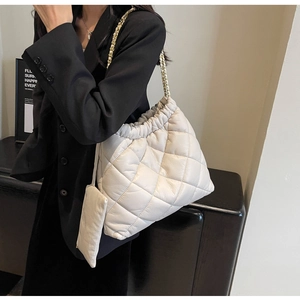 Detail of white quilted bucket bag with gold chain strap and mini zipper pouch