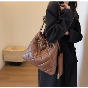 Detail view of coffee brown quilted shoulder bag with chain strap and mini purse pendant
