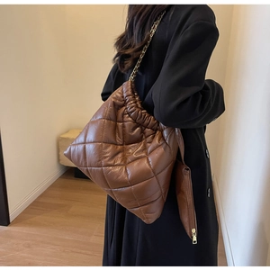 Detail of brown quilted bucket bag with chain strap and matching small zipper pouch
