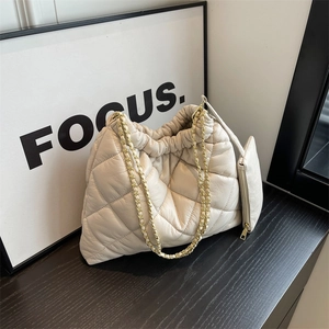 Chic beige quilted cloud shoulder bag with gold chain strap and mini pouch on black wood