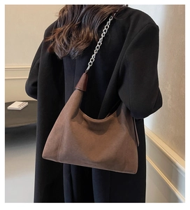 Détail du sac sous le bras en daim avec chaîne argentée et garniture en cuir brun