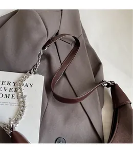Détail du sac sous le bras en daim avec chaîne métallique et bandoulière en cuir