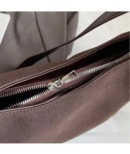 Gros plan détaillé sur le zip en métal argenté lisse d'un sac bandoulière en daim marron