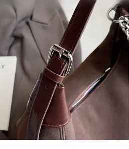 Gros plan du sac cabas en cuir marron et daim avec boucle en métal argenté et coutures
