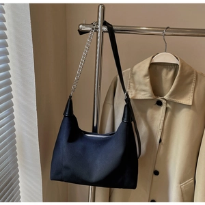 Détail du sac fourre-tout noir avec chaîne argentée suspendu sous une lumière naturelle