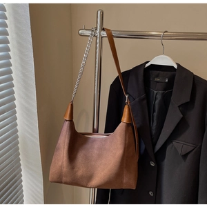 Détail du sac bandoulière en daim marron avec logo CHERIMATE et bandoulière chaîne