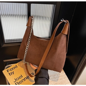 Détail du sac hobo en daim marron avec large bandoulière et chaîne métallique argentée