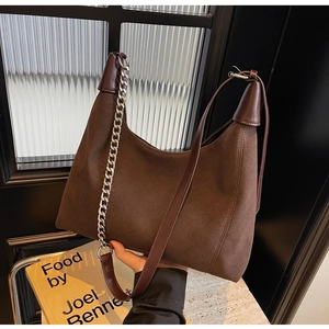 Détail du sac hobo en cuir mat marron foncé avec chaîne en métal et bandoulière