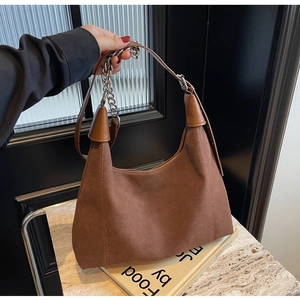 Détail du sac hobo en daim marron avec bandoulière en chaîne et logo de la marque