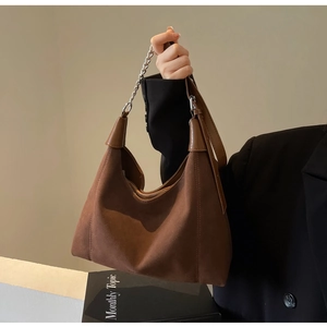 Détail du sac hobo en daim marron avec bandoulière chaîne et fermeture éclair