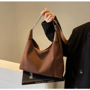 Détail du sac hobo en daim avec chaîne argentée et texture de cuir marron mat
