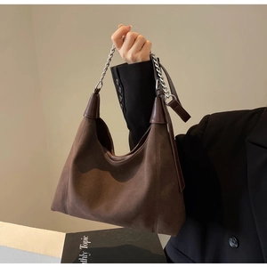 Détail du cabas en daim marron foncé avec chaîne argentée et accents en cuir mat élégants