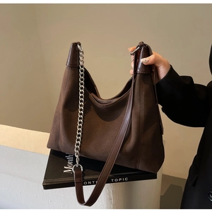 Détail du sac Hobo en daim marron foncé avec chaîne argentée et finitions en cuir lisse