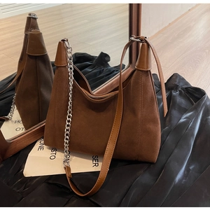 Détail de sac porté épaule en daim marron avec chaîne argentée et bandoulière en cuir