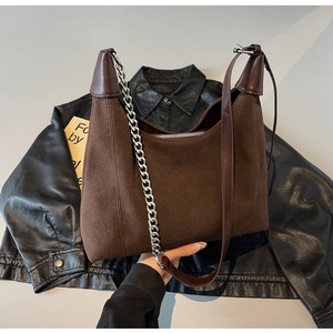 Détail du sac bandoulière en daim marron avec chaîne argentée et textures de cuir mixtes