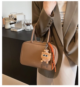 Close-up of brown litchi pattern leather bowling bag with cute plush bear charm