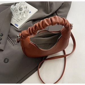 Macro shot of brown pleated crescent bag interior featuring zipper pocket and lining