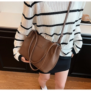 Macro view of vertical pleated texture on brown PU leather bucket bag with shoulder strap