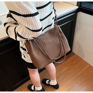 Detail view of large dark brown pleated bucket bag worn by a model in a minimal setting