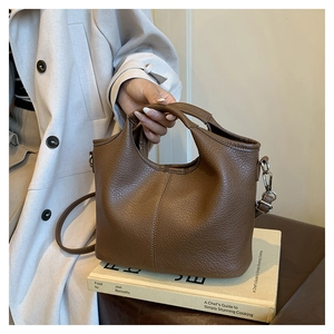Detailed macro view of brown lychee-patterned leather bucket bag with top handle and strap