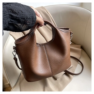 Detail of brown litchi pattern leather bucket bag with top handle and stitching