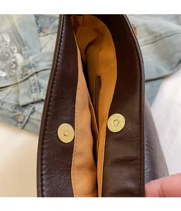 Detail view of the magnetic snap closure and fabric lining on the vintage brown shoulder bag