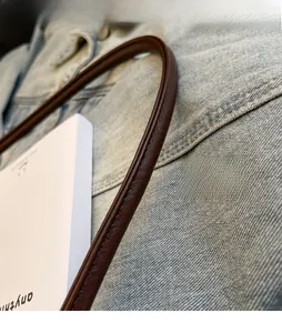 Detail of reinforced shoulder strap with professional stitching on a dark brown leather bag