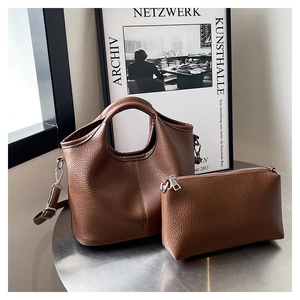 Close-up of brown pebbled leather tote bag and zipper pouch on a metal table