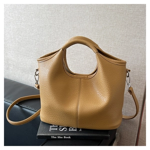 Detailed macro view of the camel lychee grain leather texture and silver hardware on bucket bag