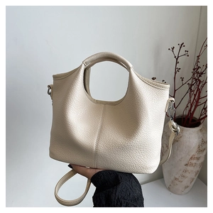 Detail of cream lychee leather bucket bag showing grain texture and silver hardware