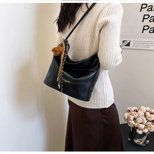 Detail of black large capacity shoulder bag with bear charm and striped silk scarf decor
