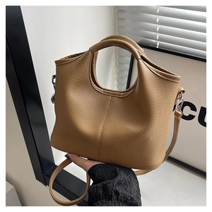 Detail of tan lychee textured leather bucket bag with silver hardware and shoulder strap