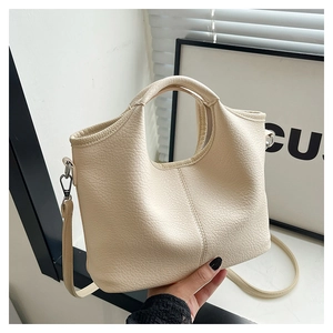 Detail of creamy white bucket bag in lychee pattern leather with dual carrying handles
