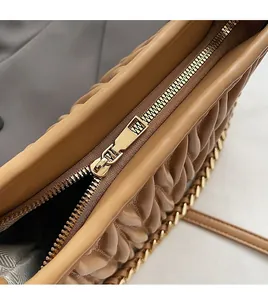 Dettaglio della texture in pelle marrone trapuntata con cerniera dorata fluida e lucida