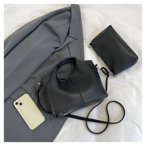Detail of black lychee leather bucket bag set with matching pouch on white fabric
