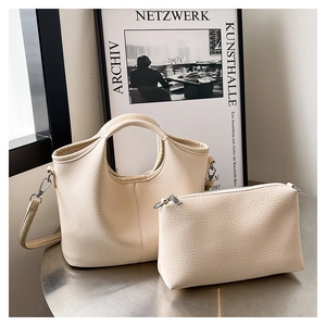 Detail of cream lychee texture tote bag and matching pouch on a silver metal stand