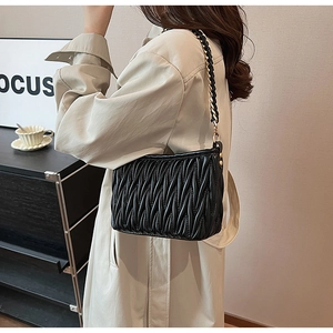Dettaglio borsa a spalla in pelle nera matelassé con catena dorata intrecciata decorativa