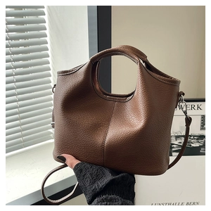 Close-up of brown pebbled leather texture and round hollow handle on minimalist bucket bag