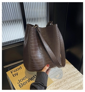 Detail of dark brown faux crocodile bucket bag texture on a stone surface