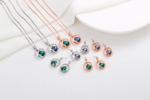 Detailed view of crystal pendant necklaces and matching earrings in green and purple hues