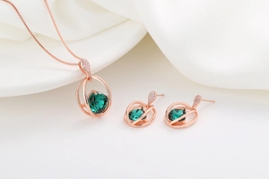 Macro shot of rose gold jewelry set featuring emerald green stones and diamond accents