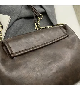 Detail showing deep brown vintage textured leather and golden chain on a shoulder bag
