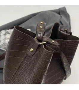 Detailed close-up of dark brown crocodile pattern bucket bag with shiny gold hardware accents