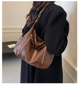 Detail of dark brown hobo shoulder bag with metal zippers and golden hardware accent