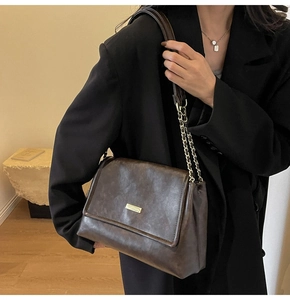 Detail of dark brown vintage faux leather crossbody bag with gold chain strap and square lock