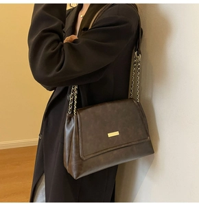 Close-up of vintage brown leather bag featuring gold hardware and metal chain strap