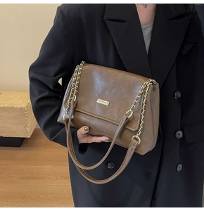 Detail of vintage brown leather crossbody bag with gold metal plate and chain strap