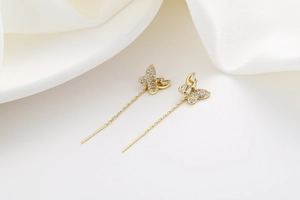Close-up of elegant butterfly tassel earrings with sparkling crystals on white silk