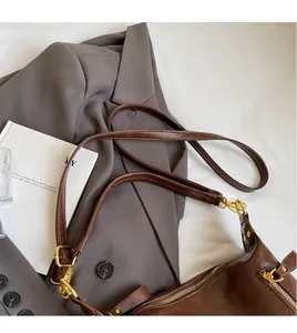 Detail of adjustable shoulder strap and gold hardware on dark brown leather tote bag