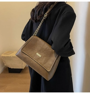 Detail of coffee brown vintage crossbody bag with gold buckle and chain leather strap